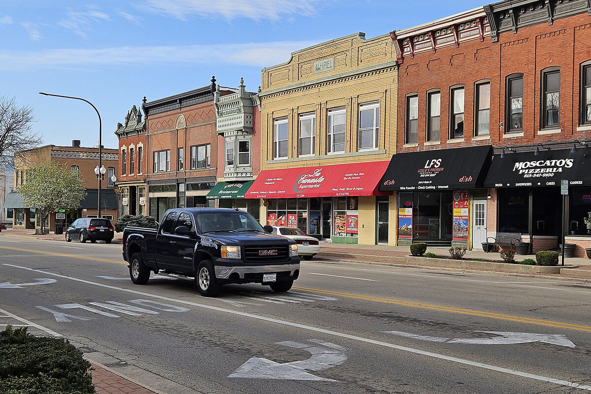 A pickup truck drives past red and yellow brick storefronts in Belvidere, Illinois.